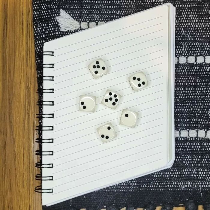 White dice scattered on a lined spiral notebook, illustrating imperfect things that annoy people with OCD.