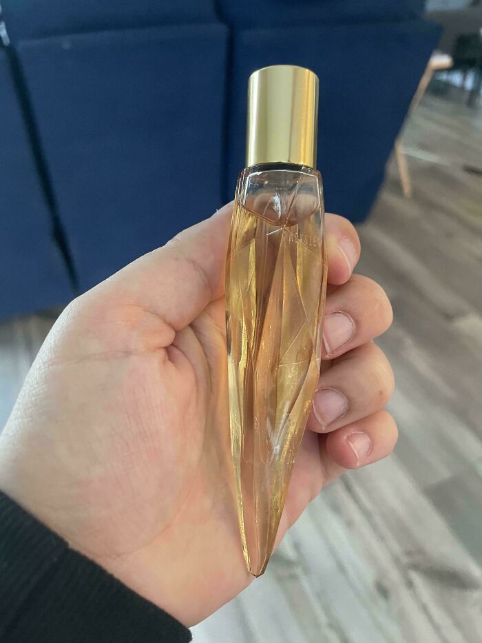 Hand holding a c*****d, imperfect glass perfume bottle, illustrating things that annoy people with OCD.