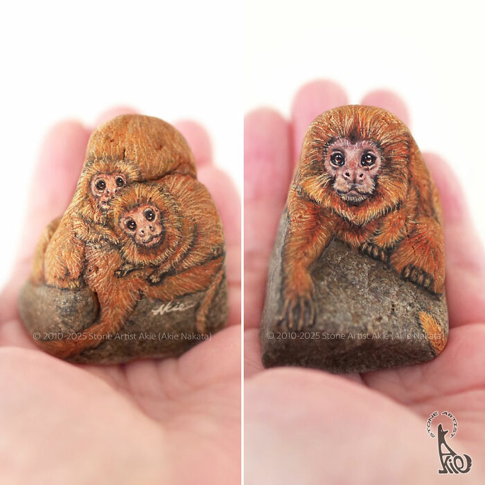 Small stones painted by Japanese artist into adorable animals resembling monkeys held gently in hands.