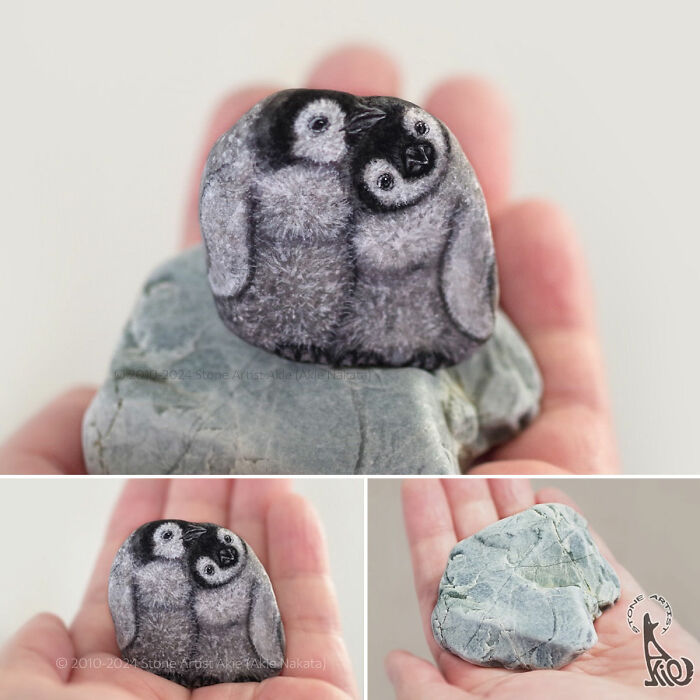 Hand holding a stone painted by Japanese artist to resemble two adorable penguin chicks in fine detail.