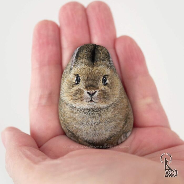 Hand holding a stone painted to look like an adorable animal by a Japanese artist turning stones into cute creatures.