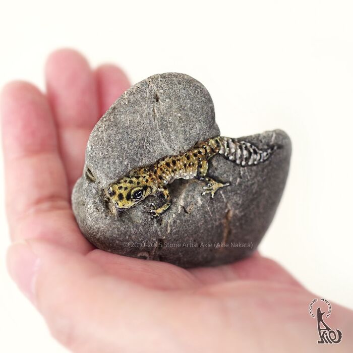 Hand holding a stone painted by Japanese artist to resemble an adorable small spotted animal.