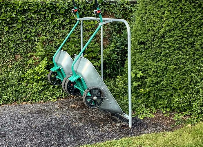 Two wheelbarrows hanging on a metal rack outdoors, showcasing a genius solution to garden storage problems.