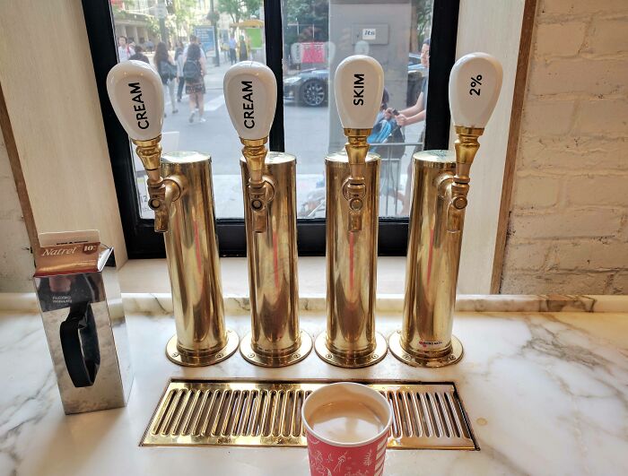 Four brass cream and milk dispensers labeled cream, skim, and 2%, set on marble counter as a genius solution for easy pouring.