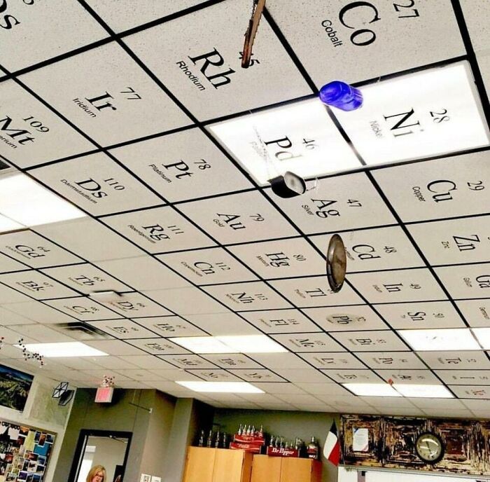 Ceiling tiles printed as a periodic table with hooks and objects hanging, showcasing a genius solution in a classroom.