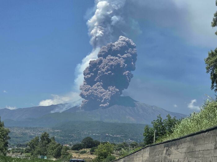 Volcanic eruption with massive ash cloud rising against clear sky in a stunning world geography landscape.