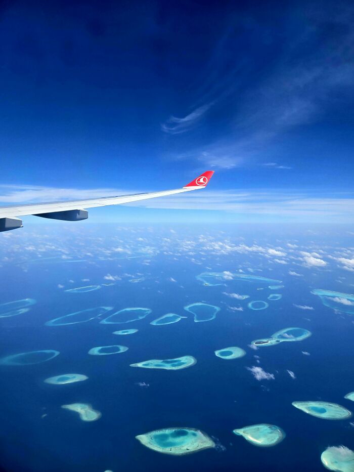 Aerial view of turquoise islands and coral reefs over deep blue ocean, showcasing fascinating photos of world geography.