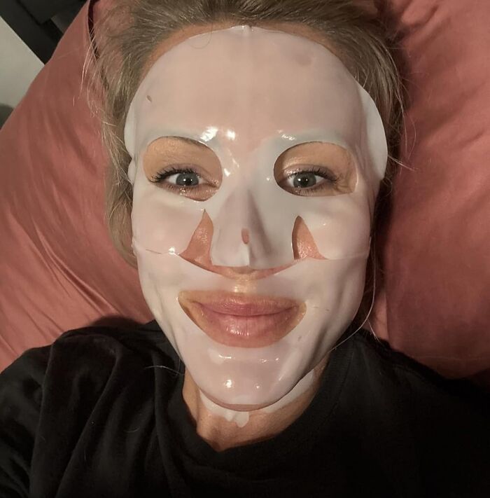 Woman wearing a moisturizing face mask while relaxing on a pillow, showcasing one of the most-wished-for Amazon finds.
