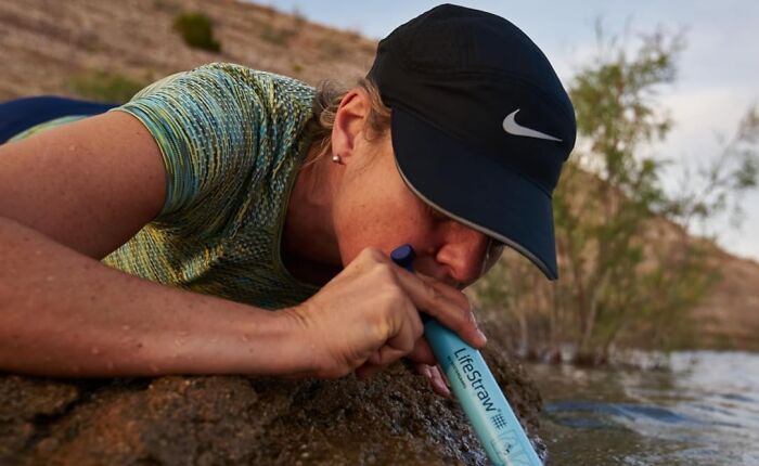 Person using a LifeStraw water filter outdoors, demonstrating one of the most-wished-for Amazon finds for survival and adventure.