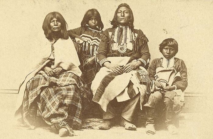 Vintage Native American family photo showing traditional clothing and cultural heritage in a historic black and white image.