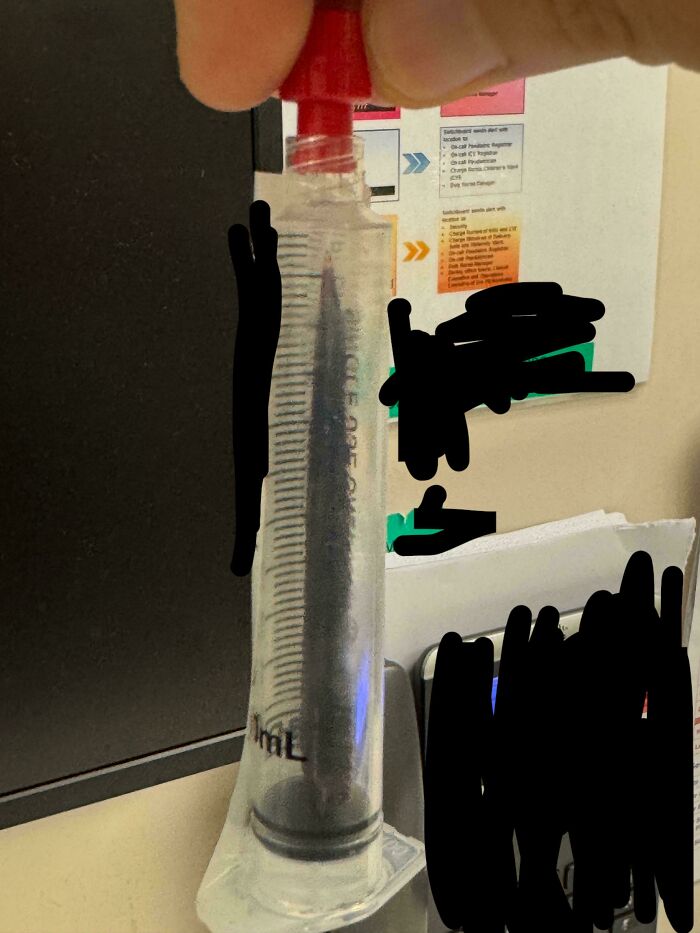 Close-up of a medical syringe held by hand, showcasing detailed measurement markings in a clinical setting.