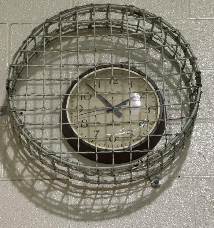 Old school wall clock protected by a worn metal cage, illustrating schools that are not created equal or great.