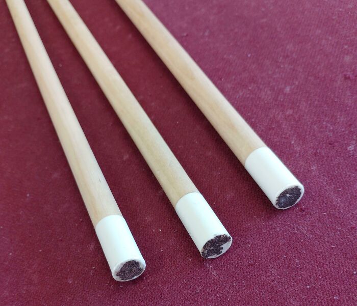 Three wooden pool cues with white tips placed on a red surface highlighting school tools not all schools are equal.