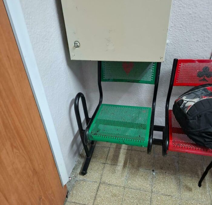 Metal school chairs in a hallway corner, showing wear and uneven setup, highlighting inequality in school facilities.