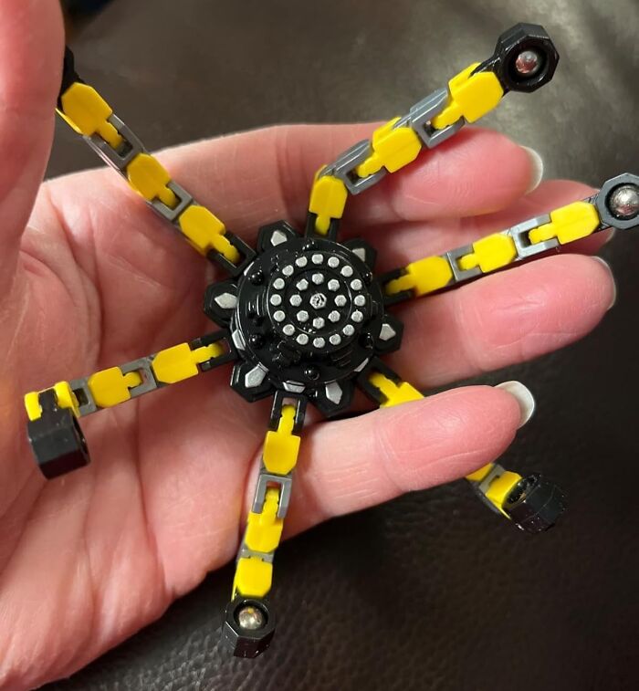 Hand holding a yellow and black toy with multiple flexible arms, featured in toys under 20 dollars gift ideas.
