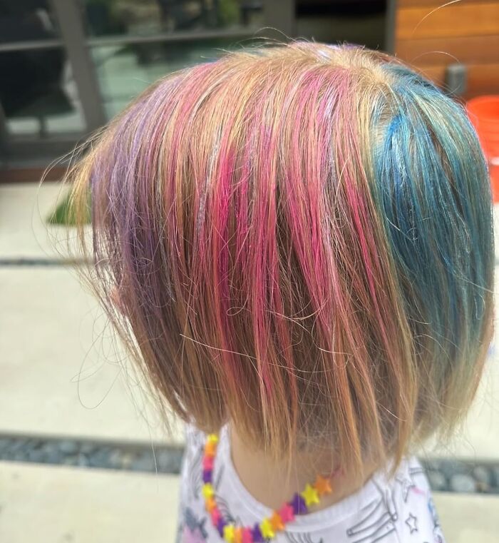 Child with rainbow-colored streaks in hair wearing a star bead necklace, illustrating creative toys under 20 dollars.