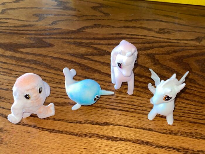 Four small plush animal toys including an octopus, narwhal, unicorn, and dragon on a wooden surface under $20.