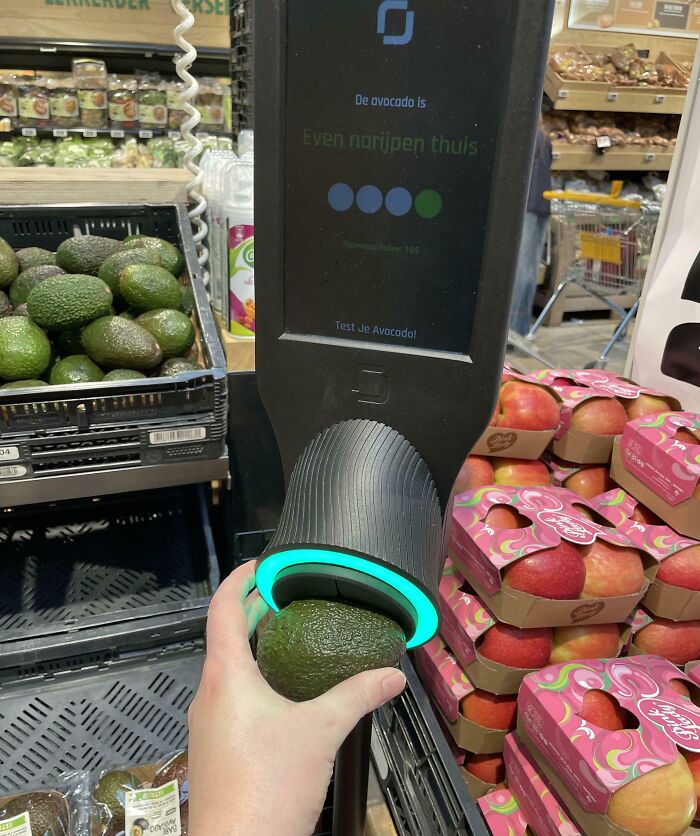 Avocado ripeness tester device in a grocery store with hand holding avocado for a quick quality check.