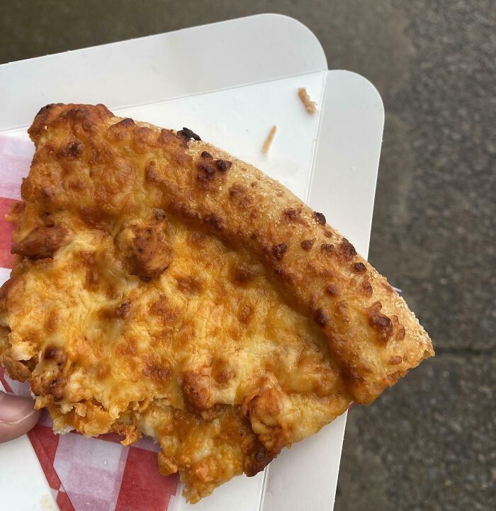 Slice of cheese pizza with uneven toppings, illustrating differences in quality among schools and their food offerings