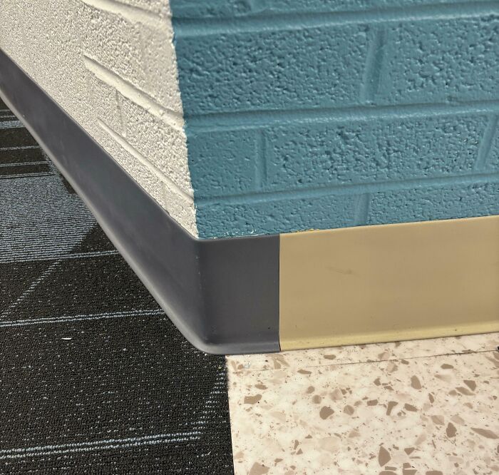 Corner of a school wall with mismatched baseboards and flooring showing a lack of quality in school construction.