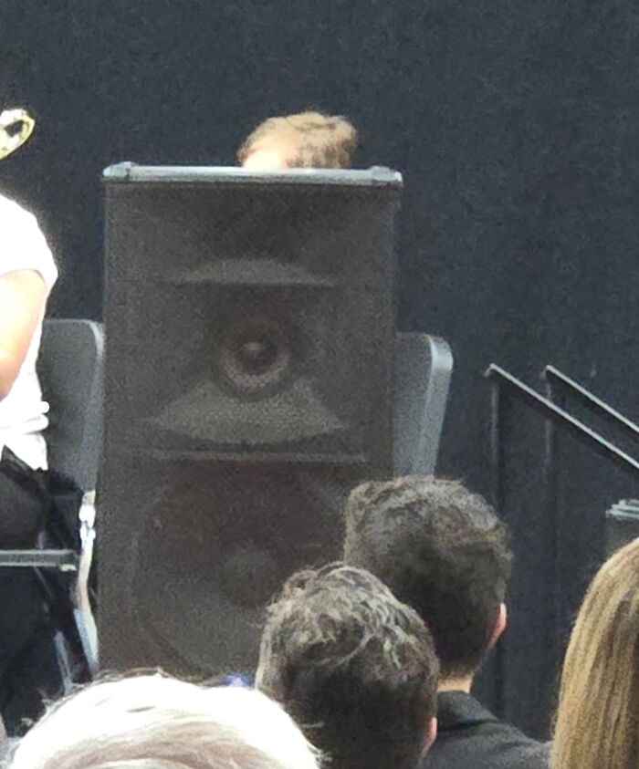 Person's head hidden behind large speaker during a school event highlighting schools are not created equal.