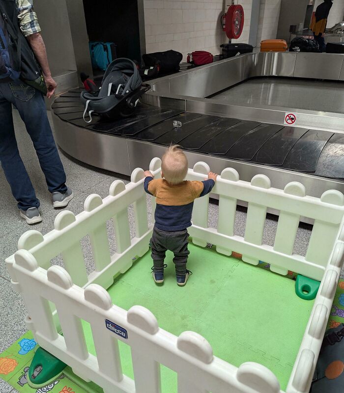 Child safely enclosed in a playpen at an airport baggage claim demonstrating real-world design genius.