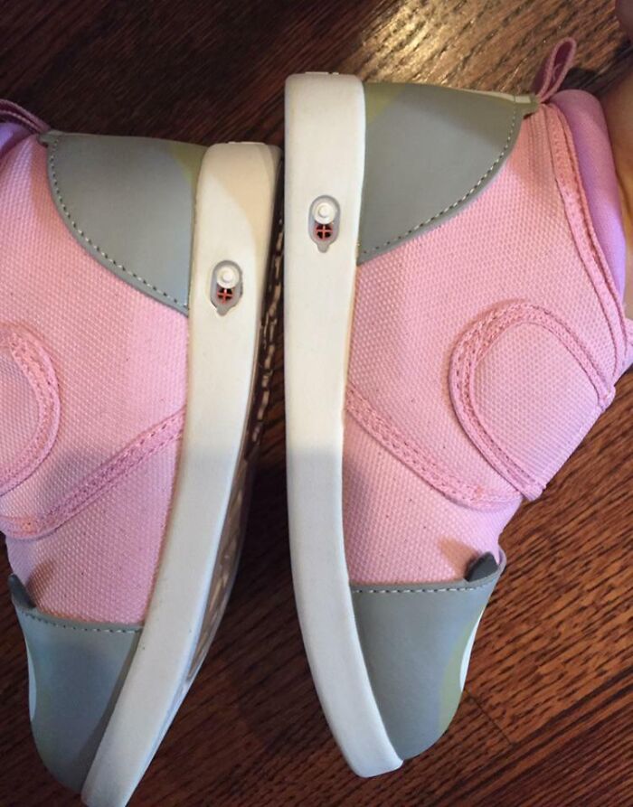 Pink shoes with gray accents resting on a wooden floor, showcasing a clever adjustment solution for hassle-free wear.