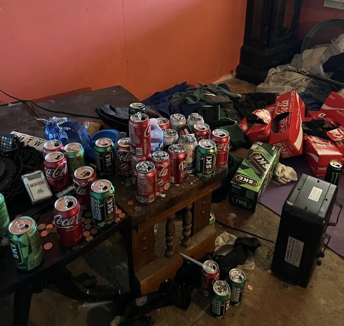 Cluttered room with empty soda cans, cardboard boxes, and scattered clothes illustrating bad roommate habits.