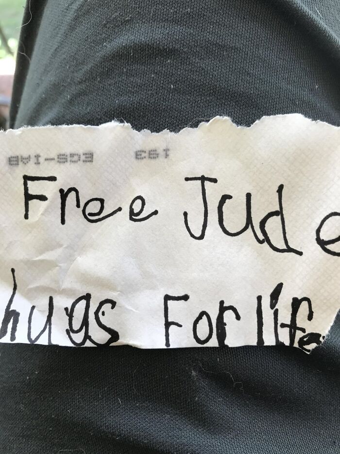 Note with handwriting offering free hugs on black fabric, representing the beauty of planet Earth through kindness and connection.