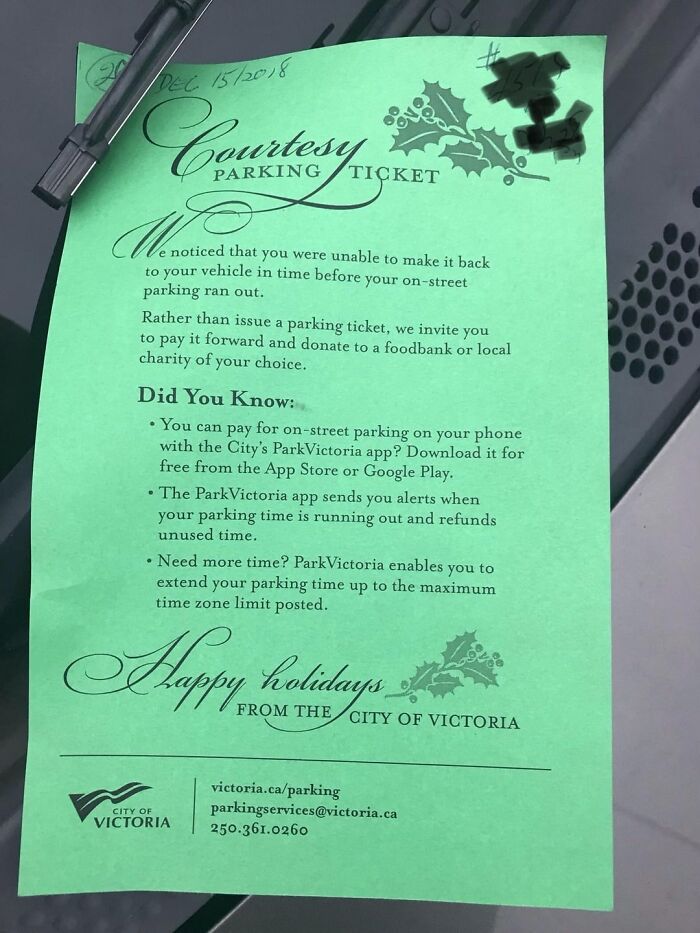 Green courtesy parking ticket on a car windshield with holiday decorations, highlighting beauty of planet earth.