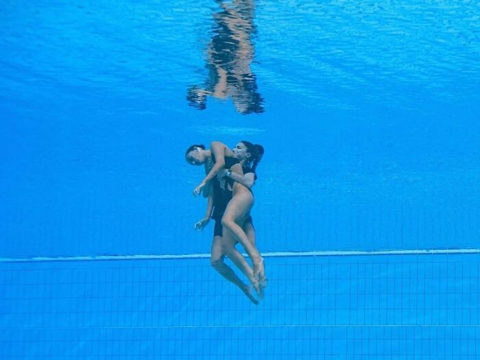 Two people gently embracing underwater in a clear blue pool showing the beauty of planet Earth.