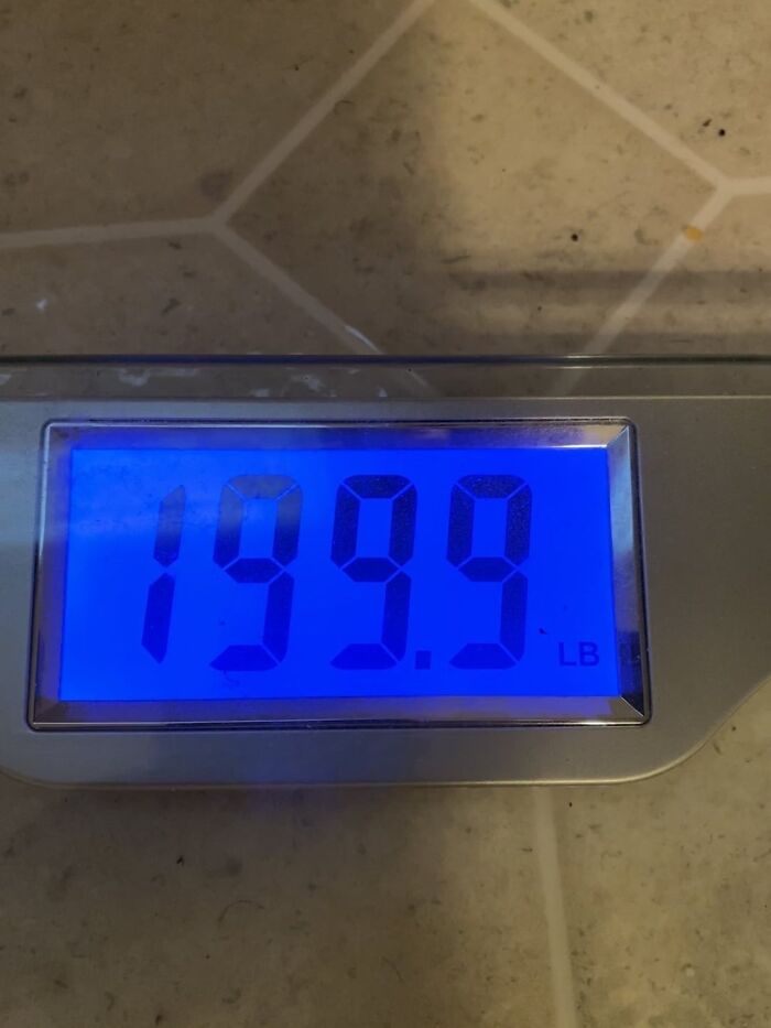 Digital bathroom scale showing a weight of 199.9 pounds on tiled floor reflecting the beauty of planet earth.