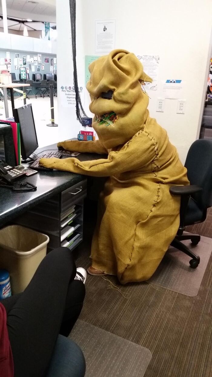 Person in a burlap costume sitting at a desk with computer in an office, capturing the beauty of planet Earth theme.