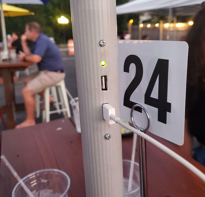 USB charging port built into outdoor table pole by table number 24, showcasing genius real-world design innovation.