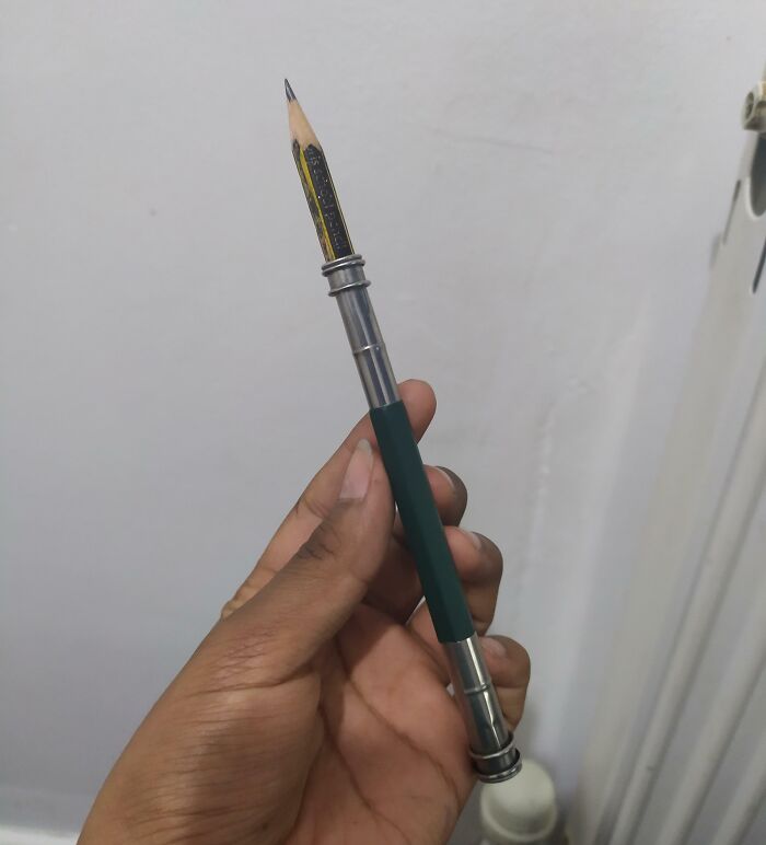 Hand holding a genius solution tool that extends a pencil for overlooked problem fixing.