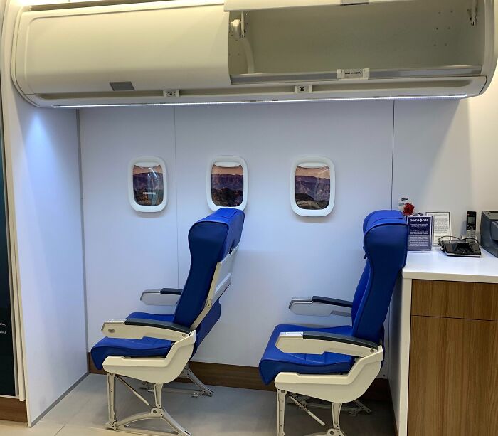 Airplane seating display with blue seats and small windows in an indoor setting showing genius solutions.