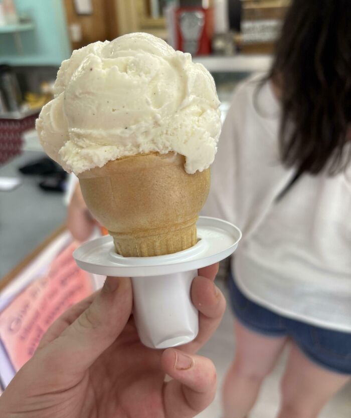 Hand holding an ice cream cone with a unique spill-proof holder, a genius solution to an overlooked problem.
