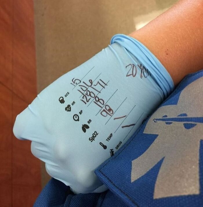 Medical photo showing a gloved hand with vital signs written on it, highlighting detailed patient monitoring.