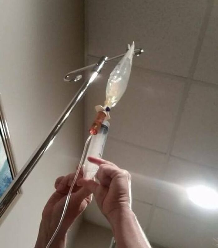 Hands adjusting an IV drip with clear fluid in a medical setting, showcasing a medical photo with fascinating details.