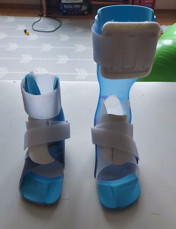 Blue medical orthopedic braces with white straps designed for foot and ankle support on a table.