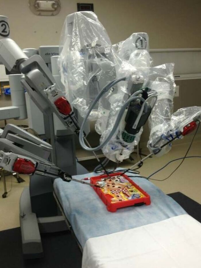 Robotic surgical system covered in plastic performing a delicate procedure with precision instruments on a medical training model.