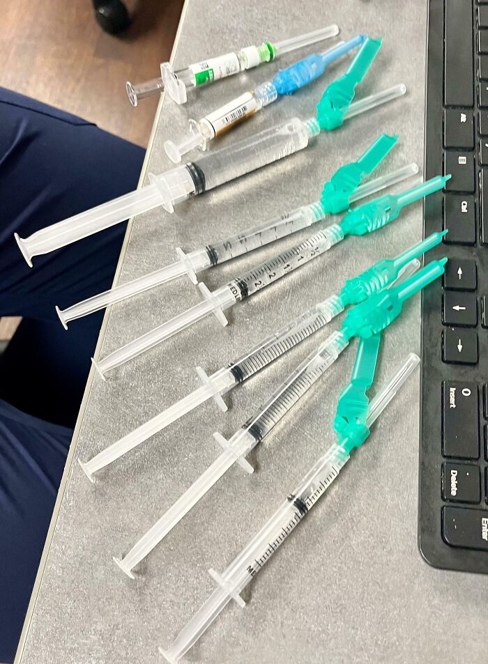 Several medical syringes with needles and caps arranged on a desk next to a keyboard, medical photos concept.
