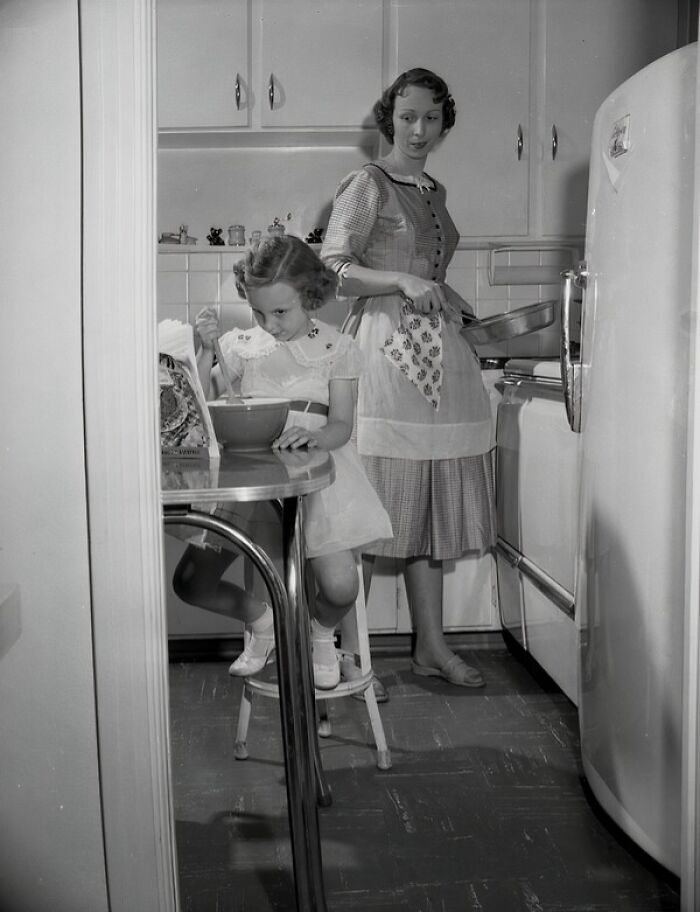 1950s Florida kitchen scene with a mother cooking and daughter stirring food at a table, showing everyday life moments