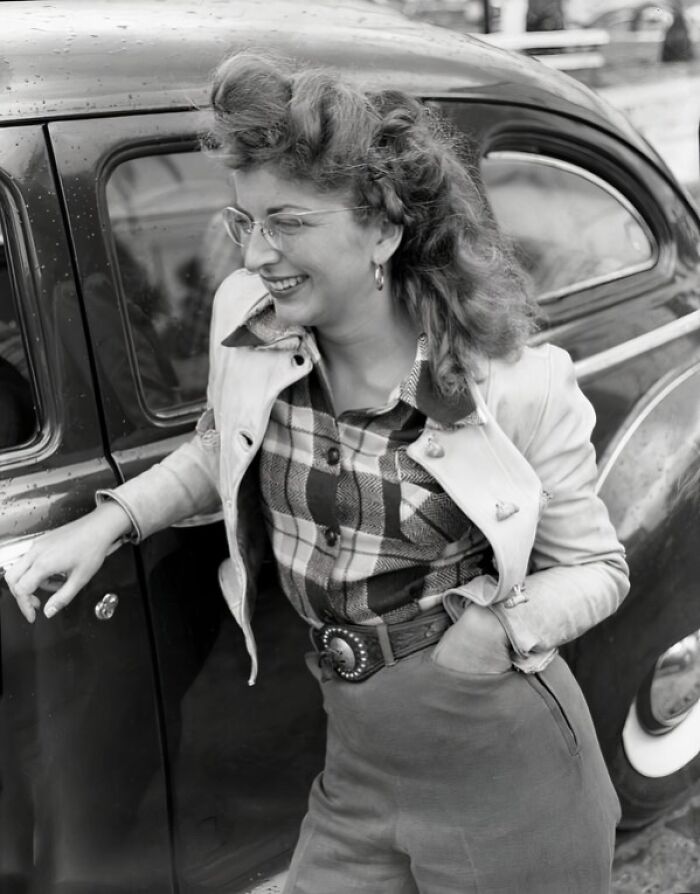 Smiling woman in 1950s attire leaning on a car, capturing everyday life in 1950s Florida with vintage style.