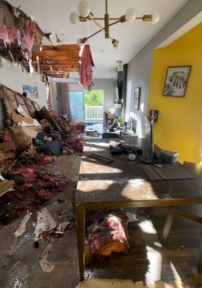 Interior of a damaged living room with exposed insulation and debris, showing chaotic neighbor tales that might make you move to the woods.