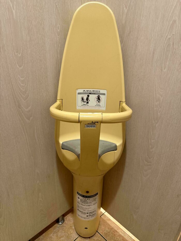 Compact wall-mounted baby seat in public restroom, showcasing small genius things some countries do for convenience and safety.