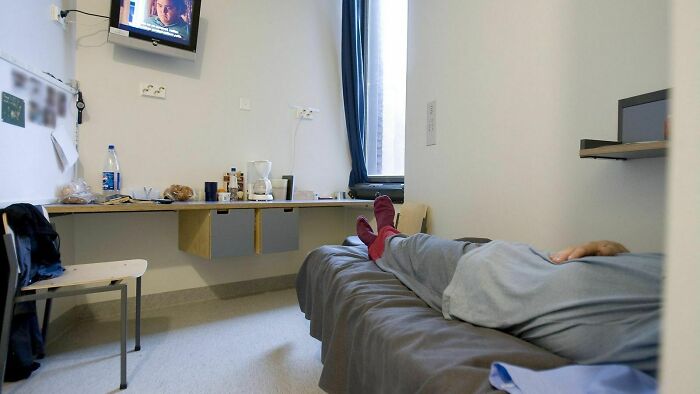 Person resting on a bed in a minimalistic room, illustrating small but genius things some countries do for efficiency.