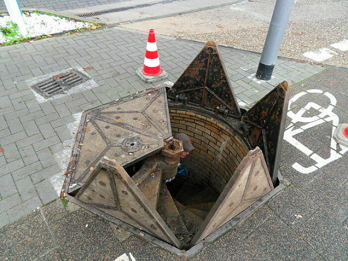 Small but genius street design in urban area featuring a unique foldable manhole cover, highlighting smart city solutions.