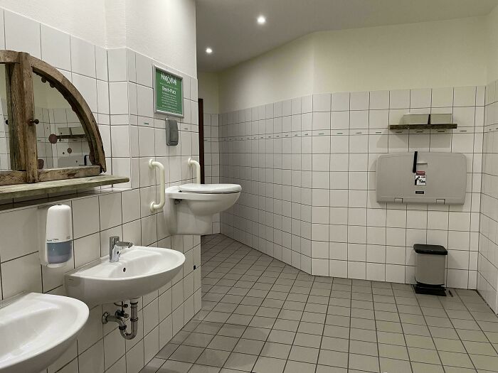 Clean and spacious public restroom with wall-mounted sinks and toilet, showcasing small but genius country design ideas.