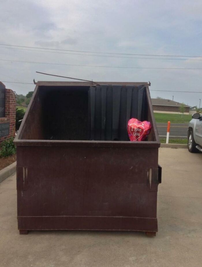 Heart-shaped balloon saying I love you discarded inside a dumpster, symbolizing brutal rejection and emotional dismissal.